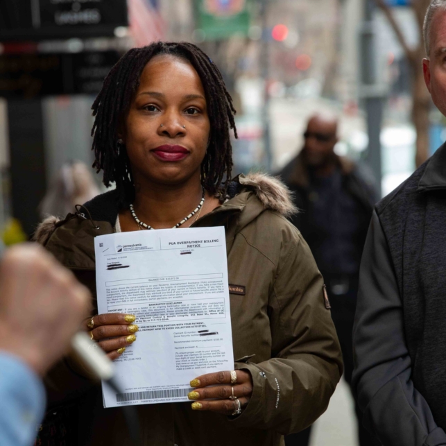 A portrait of a Black woman holding a pandemic unemployment assistance overpayment notice.
