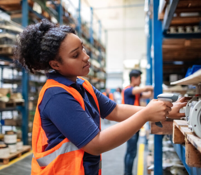 A young warehouse worker scans items on a shelf