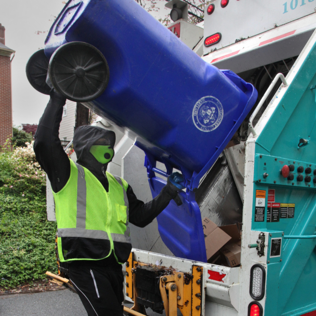 A garbage collector places recycling into a truck.