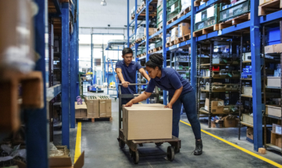 Distribution warehouse workers moving boxes in plant. Man and woman in uniform working in a large warehouse.