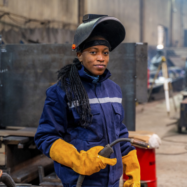 A young Black university student is practicing her welding skills.