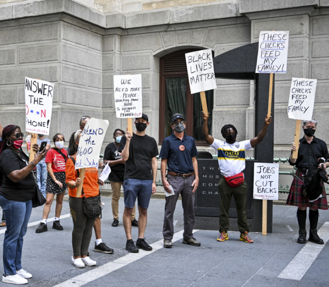 A group of unemployed workers hold signs at an action.