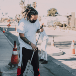 Two workers in athletic clothing sweep debris in the street