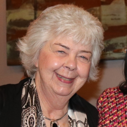 Headshot of a smiling woman with white short hair