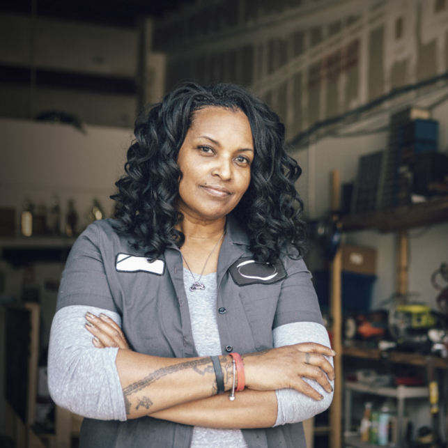 A woman mechanic looks directly into the camera.