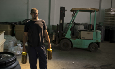 A man holds two olive carafes in a warehouse.