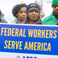 A group of Black government workers attend a rally. A woman wearing an AFGE cap holds a blue and yellow sign that reads, "Federal Workers Serve America". Photo source: American Federation of Government Employees (AFGE)