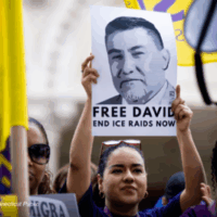 A woman holds up a sign that reads, "Free David: End ICE Raids Now." Photo credit: Tyler Russell, Connecticut Public.