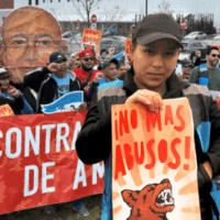 Worker advocates with Make the Road New Jersey rally for Amazon accountability. A Latine woman worker wearing a black baseball cap and Amazon Flex vest holds a sign that reads, "NO MAS ABUSOS!" Amazon Flex, app-based work, independent contractor misclassification, mandatory arbitration, forced arbitration, class action waivers, algorithmic management, digital surveillance, bossware, corporate accountability, worker data rights