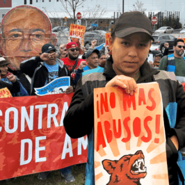 Worker advocates with Make the Road New Jersey rally for Amazon accountability. A Latine woman worker wearing a black baseball cap and Amazon Flex vest holds a sign that reads, "NO MAS ABUSOS!" Amazon Flex, app-based work, independent contractor misclassification, mandatory arbitration, forced arbitration, class action waivers, algorithmic management, digital surveillance, bossware, corporate accountability, worker data rights