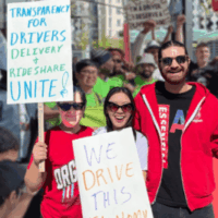 A trio of workers with Colorado Independent Drivers United wearing red, carry signs that say, 'Transparency for Drivers - Delivery and Rideshare Unite!', and 'We Drive This Economy'.