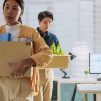 Workers experiencing a layoff walking with personal belongings boxes.