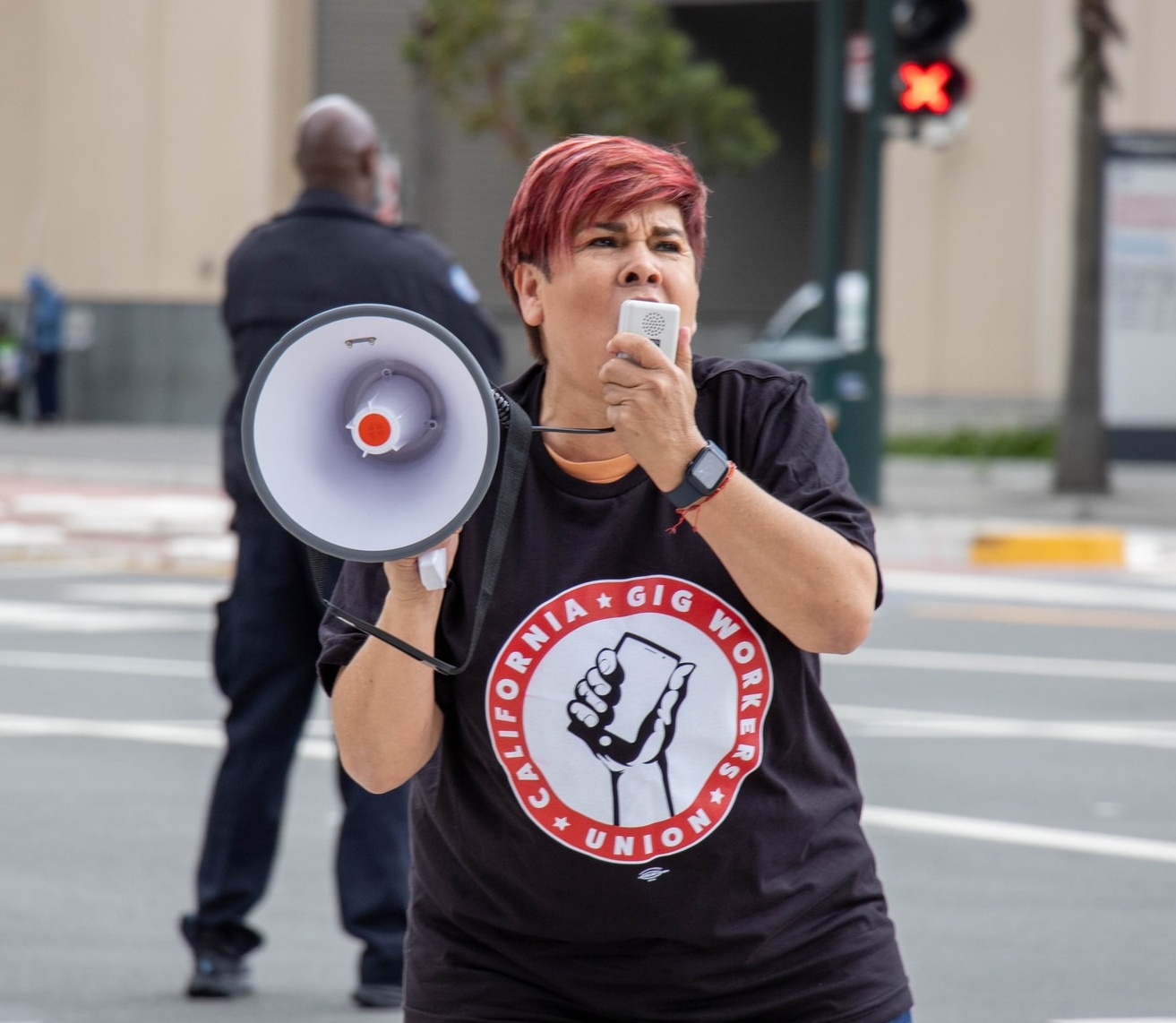 A California Gig Workers Union member speaks on a bullhorn at a driver's action